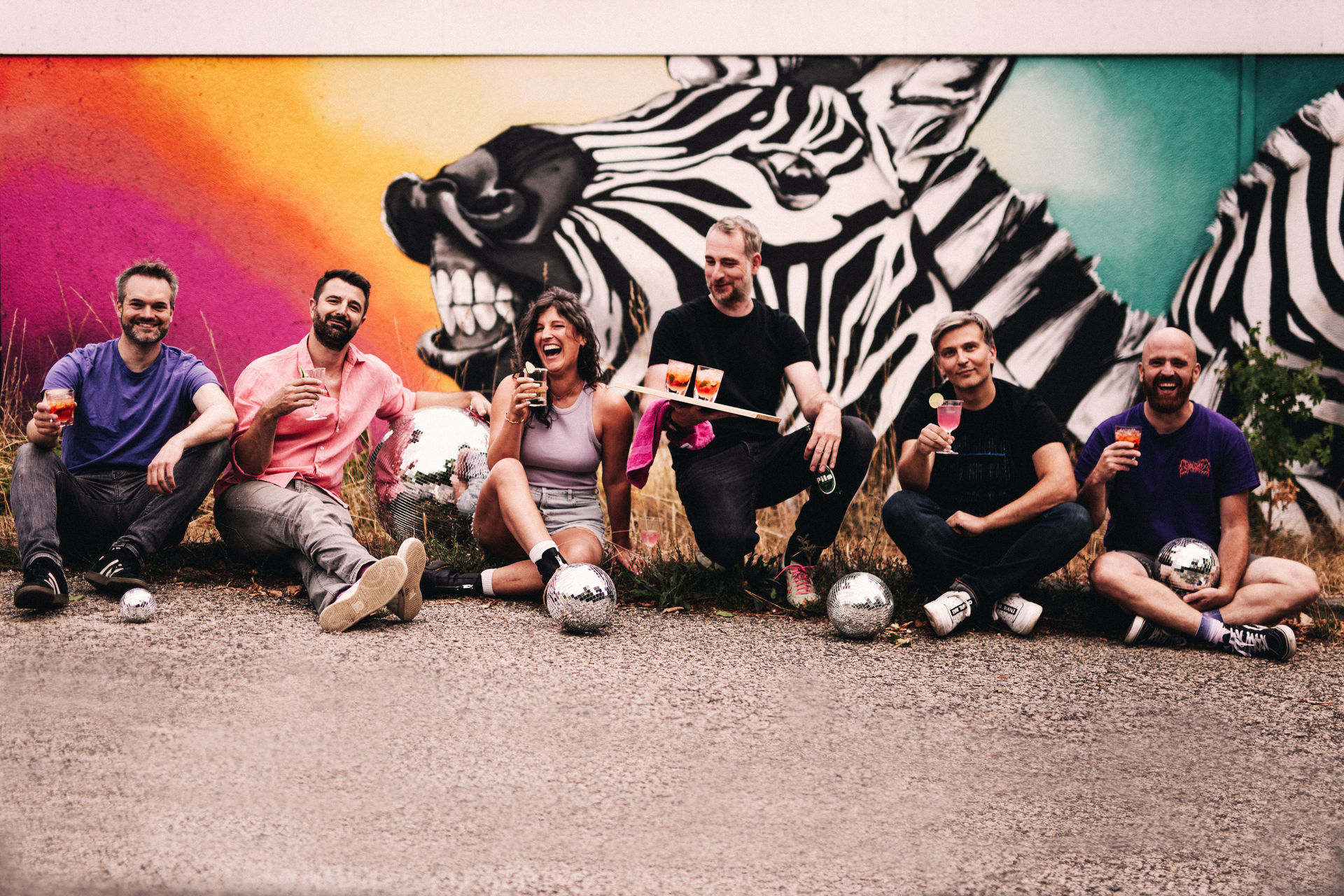 Diskoschorle Deluxe mit Discokugeln und Schorle vor dem Zebra-Graffiti